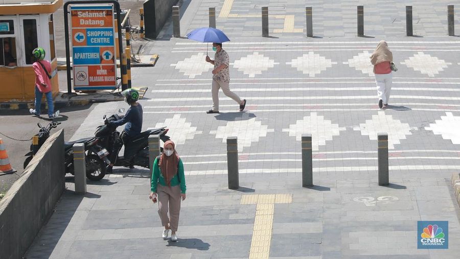 Sejumlah pekerja melintas di jalur pedestrian di kawasan Senayan Sudirman, Jakarta, Jumat (12/5/2023). (CNBC Indonesia/Muhammad Sabki)