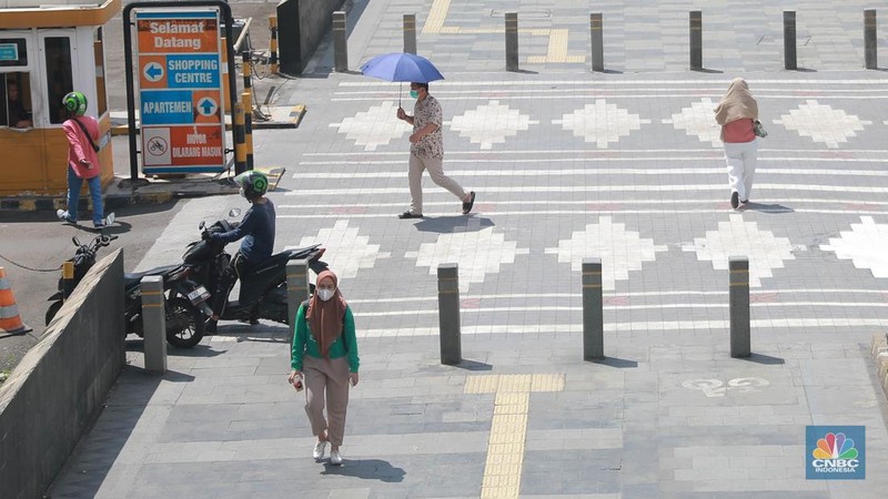 Sejumlah pekerja melintas di jalur pedestrian di kawasan Senayan Sudirman, Jakarta, Jumat (12/5/2023). (CNBC Indonesia/Muhammad Sabki)