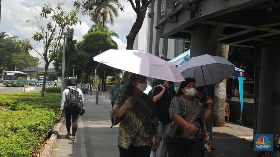 Sejumlah pekerja melintas di jalur pedestrian di kawasan Senayan Sudirman, Jakarta, Jumat (12/5/2023). (CNBC Indonesia/Muhammad Sabki)