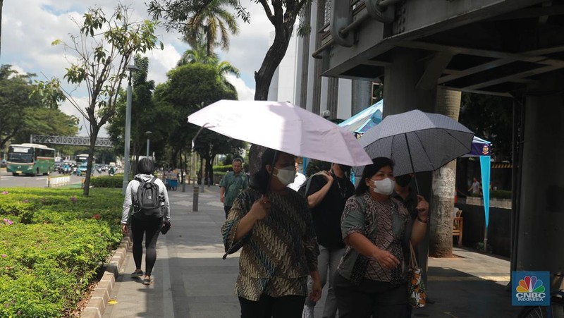 Sejumlah pekerja melintas di jalur pedestrian di kawasan Senayan Sudirman, Jakarta, Jumat (12/5/2023). (CNBC Indonesia/Muhammad Sabki)