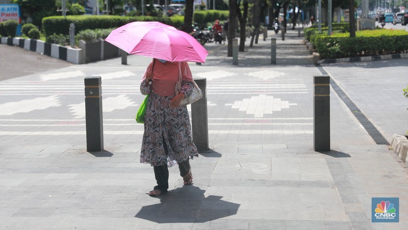 Sejumlah pekerja melintas di jalur pedestrian di kawasan Senayan Sudirman, Jakarta, Jumat (12/5/2023). (CNBC Indonesia/Muhammad Sabki)