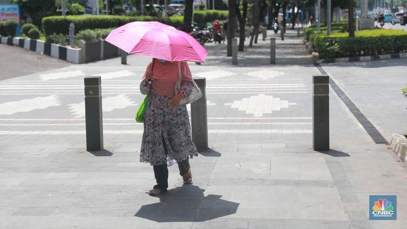 Sejumlah pekerja melintas di jalur pedestrian di kawasan Senayan Sudirman, Jakarta, Jumat (12/5/2023). (CNBC Indonesia/Muhammad Sabki)