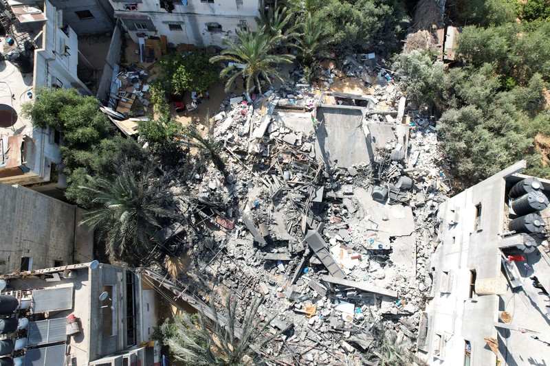 Palestinians stand on the remains of their destroyed houses, which were damaged in an Israeli strike during Israel-Gaza fighting, after a ceasefire was agreed between Palestinian factions and Israel, in Deir Al-Balah, central Gaza Strip May 14, 2023. REUTERS/Ibraheem Abu Mustafa