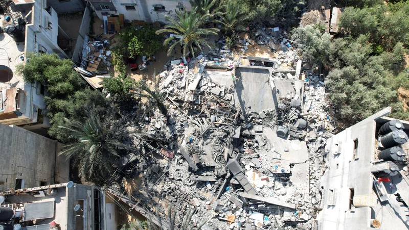 Palestinians stand on the remains of their destroyed houses, which were damaged in an Israeli strike during Israel-Gaza fighting, after a ceasefire was agreed between Palestinian factions and Israel, in Deir Al-Balah, central Gaza Strip May 14, 2023. REUTERS/Ibraheem Abu Mustafa