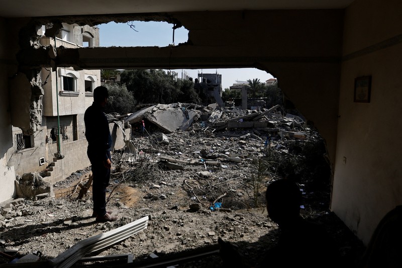 Palestinians stand on the remains of their destroyed houses, which were damaged in an Israeli strike during Israel-Gaza fighting, after a ceasefire was agreed between Palestinian factions and Israel, in Deir Al-Balah, central Gaza Strip May 14, 2023. REUTERS/Ibraheem Abu Mustafa
