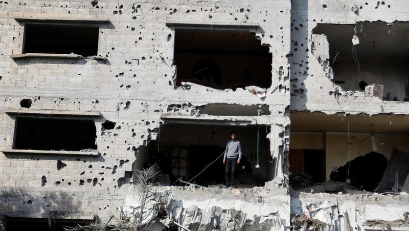 Palestinians stand on the remains of their destroyed houses, which were damaged in an Israeli strike during Israel-Gaza fighting, after a ceasefire was agreed between Palestinian factions and Israel, in Deir Al-Balah, central Gaza Strip May 14, 2023. REUTERS/Ibraheem Abu Mustafa