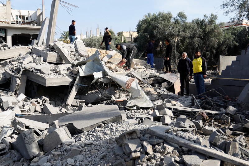 ISRAEL-PALESTINIANS/ Palestinians stand on the remains of their destroyed houses, which were damaged in an Israeli strike during Israel-Gaza fighting, after a ceasefire was agreed between Palestinian factions and Israel, in Deir Al-Balah, central Gaza Strip May 14, 2023. REUTERS/Ibraheem Abu Mustafa