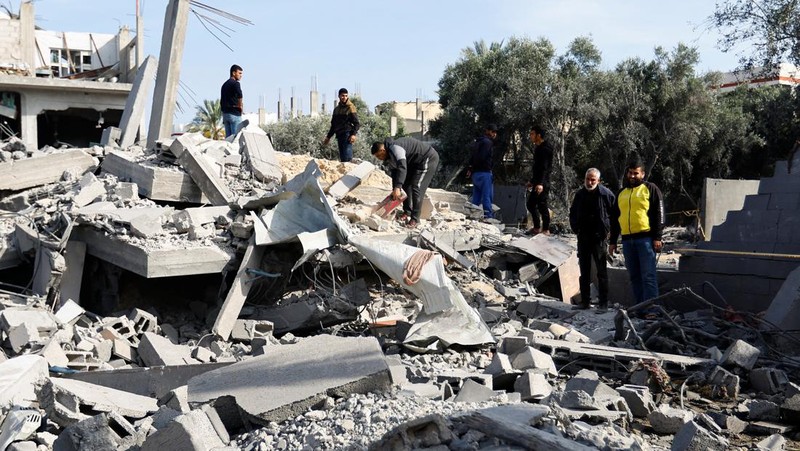 Palestinians stand on the remains of their destroyed houses, which were damaged in an Israeli strike during Israel-Gaza fighting, after a ceasefire was agreed between Palestinian factions and Israel, in Deir Al-Balah, central Gaza Strip May 14, 2023. REUTERS/Ibraheem Abu Mustafa