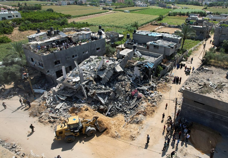 ISRAEL-PALESTINIANS/ Palestinians stand on the remains of their destroyed houses, which were damaged in an Israeli strike during Israel-Gaza fighting, after a ceasefire was agreed between Palestinian factions and Israel, in Deir Al-Balah, central Gaza Strip May 14, 2023. REUTERS/Ibraheem Abu Mustafa