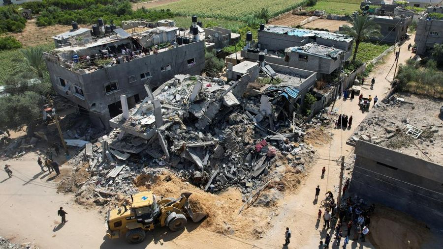 Palestinians stand on the remains of their destroyed houses, which were damaged in an Israeli strike during Israel-Gaza fighting, after a ceasefire was agreed between Palestinian factions and Israel, in Deir Al-Balah, central Gaza Strip May 14, 2023. REUTERS/Ibraheem Abu Mustafa