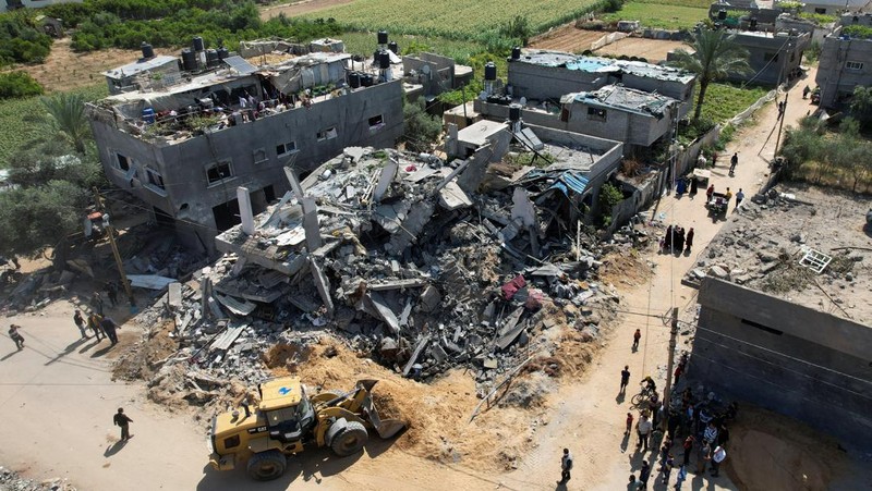Palestinians stand on the remains of their destroyed houses, which were damaged in an Israeli strike during Israel-Gaza fighting, after a ceasefire was agreed between Palestinian factions and Israel, in Deir Al-Balah, central Gaza Strip May 14, 2023. REUTERS/Ibraheem Abu Mustafa
