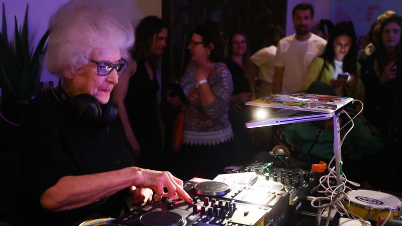 Orang-orang menari saat Wirginia Szmyt, DJ berusia 84 tahun, tampil dalam sebuah pesta di Warsawa, Polandia pada 13 Mei 2023. DJ Vika adalah DJ tertua di Polandia dan juga seorang aktivis yang bekerja untuk manula. Sebuah film dokumenter tentang DJ Vika dibuat dan ditayangkan perdana dalam beberapa hari terakhir. (Jakub Porzycki/Anadolu Agency via Getty Images)