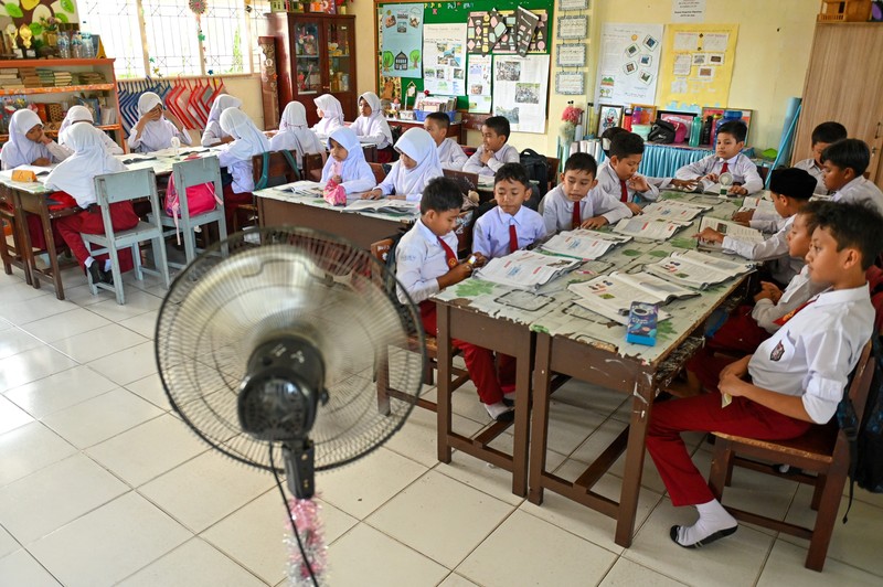 Seorang siswa sekolah dasar menggunakan kipas angin portabel untuk menjaga kesejukan saat cuaca panas di Banda Aceh pada 15 Mei 2023. Seorang siswa sekolah dasar menggunakan kipas angin portabel untuk menjaga kesejukan saat cuaca panas di Banda Aceh pada 15 Mei 2023. (CHAIDEER MAHYUDDIN/AFP via Getty Images)