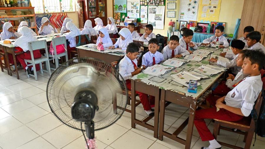Seorang siswa sekolah dasar menggunakan kipas angin portabel untuk menjaga kesejukan saat cuaca panas di Banda Aceh pada 15 Mei 2023. (CHAIDEER MAHYUDDIN/AFP via Getty Images)