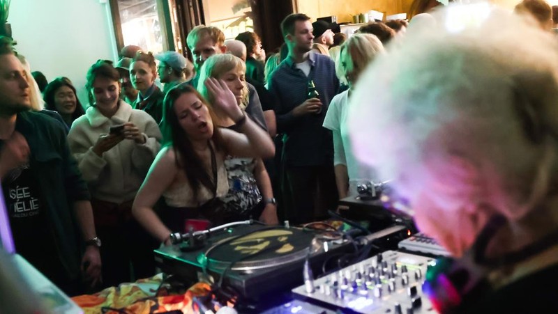 Orang-orang menari saat Wirginia Szmyt, DJ berusia 84 tahun, tampil dalam sebuah pesta di Warsawa, Polandia pada 13 Mei 2023. DJ Vika adalah DJ tertua di Polandia dan juga seorang aktivis yang bekerja untuk manula. Sebuah film dokumenter tentang DJ Vika dibuat dan ditayangkan perdana dalam beberapa hari terakhir. (Jakub Porzycki/Anadolu Agency via Getty Images)