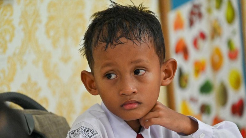 Seorang siswa sekolah dasar menggunakan kipas angin portabel untuk menjaga kesejukan saat cuaca panas di Banda Aceh pada 15 Mei 2023. (CHAIDEER MAHYUDDIN/AFP via Getty Images)