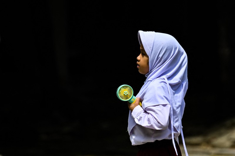 Seorang siswa sekolah dasar menggunakan kipas angin portabel untuk menjaga kesejukan saat cuaca panas di Banda Aceh pada 15 Mei 2023. Seorang siswa sekolah dasar menggunakan kipas angin portabel untuk menjaga kesejukan saat cuaca panas di Banda Aceh pada 15 Mei 2023. (CHAIDEER MAHYUDDIN/AFP via Getty Images)