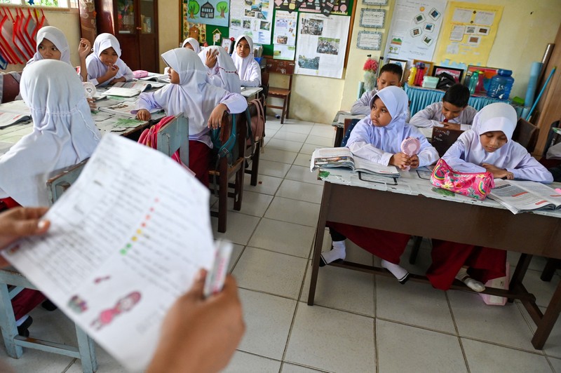 Seorang siswa sekolah dasar menggunakan kipas angin portabel untuk menjaga kesejukan saat cuaca panas di Banda Aceh pada 15 Mei 2023. (CHAIDEER MAHYUDDIN/AFP via Getty Images)