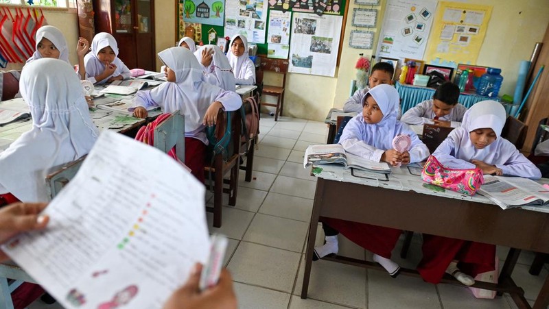 Seorang siswa sekolah dasar menggunakan kipas angin portabel untuk menjaga kesejukan saat cuaca panas di Banda Aceh pada 15 Mei 2023. (CHAIDEER MAHYUDDIN/AFP via Getty Images)