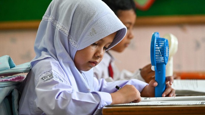 Seorang siswa sekolah dasar menggunakan kipas angin portabel untuk menyejukkan ruangan kelas saat cuaca panas di Banda Aceh pada 15 Mei 2023. (CHAIDEER MAHYUDDIN/AFP via Getty Images)
