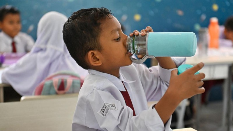 Seorang siswa sekolah dasar menggunakan kipas angin portabel untuk menjaga kesejukan saat cuaca panas di Banda Aceh pada 15 Mei 2023. (CHAIDEER MAHYUDDIN/AFP via Getty Images)