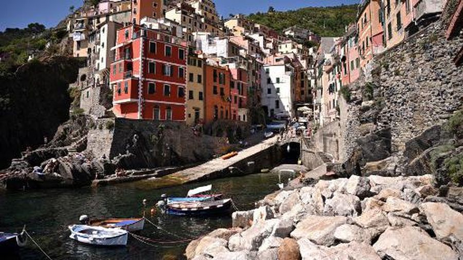 Coloured buildings are seen in the village of Riomaggiore on June 24, 2021, Cinque Terre National Park, near La Spezia, Nortwestern Italy. (Photo by MARCO BERTORELLO / AFP)