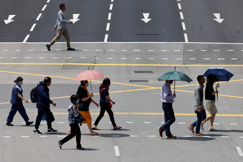 Orang-orang melindungi diri dari matahari dengan payung saat mereka menyeberang jalan pada hari yang hangat di Singapura 15 Mei 2023. Orang-orang melindungi diri dari matahari dengan payung saat mereka menyeberang jalan pada hari yang hangat di Singapura 15 Mei 2023. (REUTERS/Edgar Su)