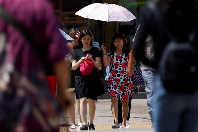Orang-orang melindungi diri dari matahari dengan payung saat mereka menyeberang jalan pada hari yang hangat di Singapura 15 Mei 2023. Orang-orang melindungi diri dari matahari dengan payung saat mereka menyeberang jalan pada hari yang hangat di Singapura 15 Mei 2023. (REUTERS/Edgar Su)
