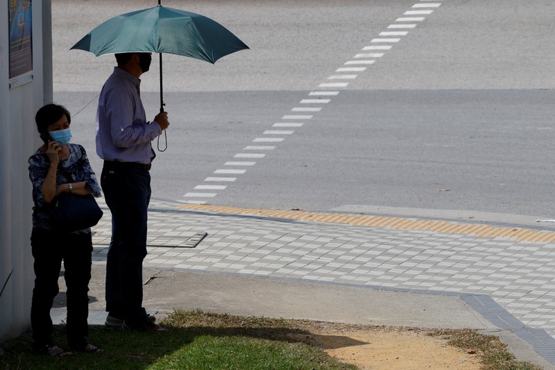 Orang-orang melindungi diri dari matahari dengan payung saat mereka menyeberang jalan pada hari yang hangat di Singapura 15 Mei 2023. Orang-orang melindungi diri dari matahari dengan payung saat mereka menyeberang jalan pada hari yang hangat di Singapura 15 Mei 2023. (REUTERS/Edgar Su)