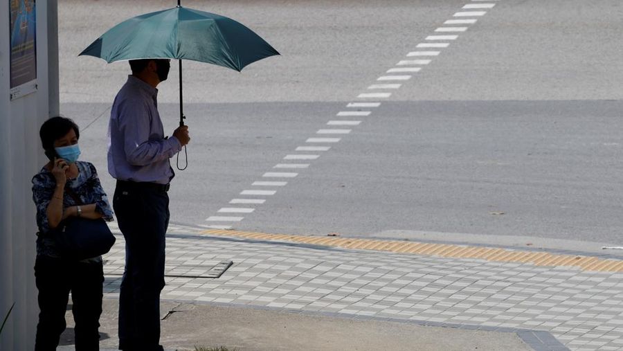 Orang-orang menunggu di tempat teduh untuk menyeberang jalan di hari yang hangat di Singapura, 15 Mei 2023. (REUTERS/Edgar Su)