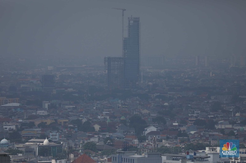 Sejumlah karyawan melihat gedung bertingkat yang tertutup oleh kabut polusi di Jakarta, Senin, (14/8). (CNBC Indonesia/Muhammad Sabki)