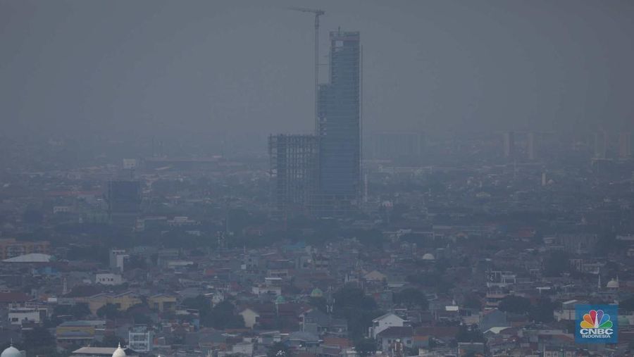 Sejumlah karyawan melihat gedung bertingkat yang tertutup oleh kabut polusi di Jakarta, Senin, (14/8). (CNBC Indonesia/Muhammad Sabki)