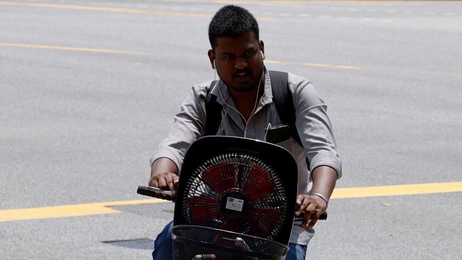 Orang-orang melindungi diri dari matahari dengan payung saat mereka menyeberang jalan pada hari yang hangat di Singapura 15 Mei 2023. (REUTERS/Edgar Su)
