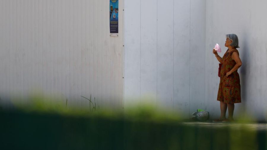 Orang-orang melindungi diri dari matahari dengan payung saat mereka menyeberang jalan pada hari yang hangat di Singapura 15 Mei 2023. (REUTERS/Edgar Su)