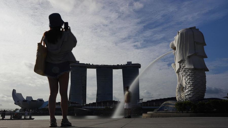 Turis berfoto di ArtScience Museum, Marina Bay Sands, dan Merlion pada 10 Mei 2023 di Singapura. (Suhaimi Abdullah/NurPhoto via Getty Images)