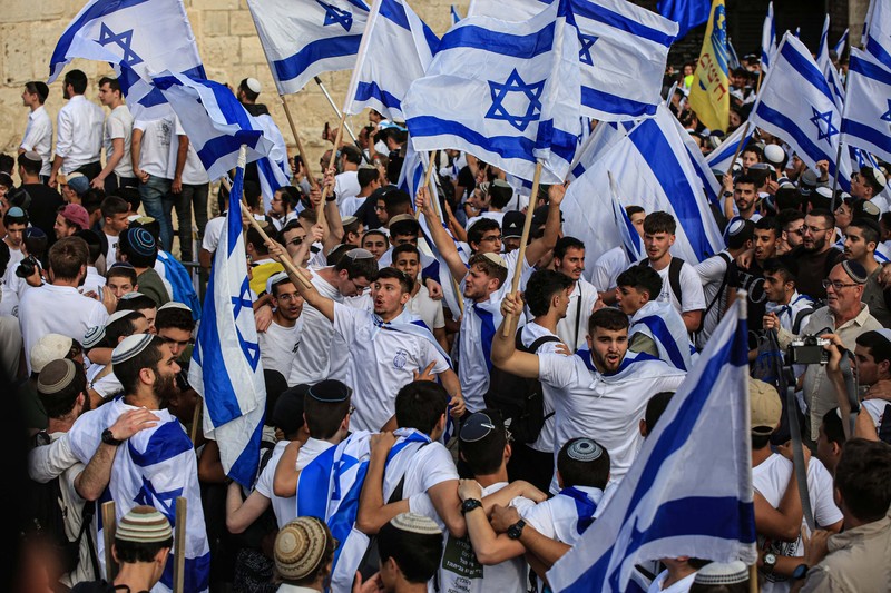 Yahudi Ultranasionalis Israel memegang bendera Israel saat mereka berbaris di kawasan Muslim kota tua Yerusalem pada 18 Mei 2023 di Yerusalem, Israel. Otoritas Israel akan mengizinkan orang-orang Yahudi Ortodoks berparade melalui Muslim Quarter Yerusalem dalam sebuah keputusan yang mengancam akan memicu kembali kekerasan di kota suci tersebut. (Amir Levy/Getty Images)