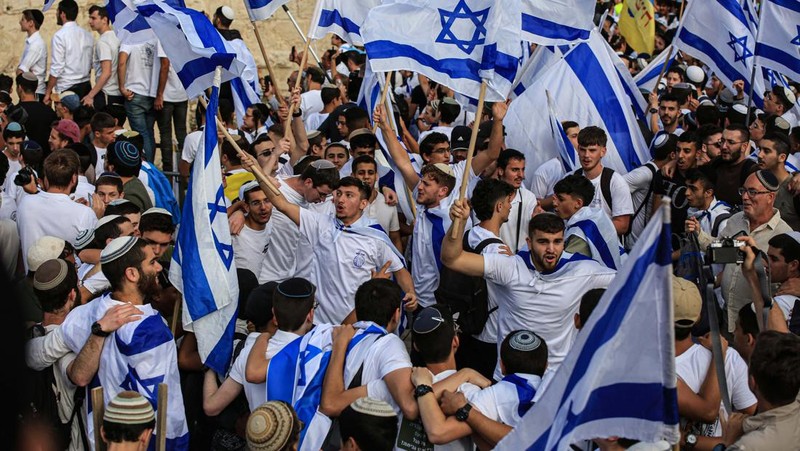 Yahudi Ultranasionalis Israel memegang bendera Israel saat mereka berbaris di kawasan Muslim kota tua Yerusalem pada 18 Mei 2023 di Yerusalem, Israel. Otoritas Israel akan mengizinkan orang-orang Yahudi Ortodoks berparade melalui Muslim Quarter Yerusalem dalam sebuah keputusan yang mengancam akan memicu kembali kekerasan di kota suci tersebut. (Amir Levy/Getty Images)