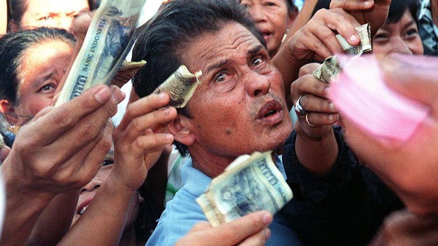 An Indonesian man scrambles to buy 3,000 rupiah worth of food coupons (about 30 US cents) to exchange for a bag of rice, sugar and cooking oil during a food distribution in Yogyakarta, Central Java 04 October. The country's economic crisis has left some 17.1 million families facing food shortages nationwide. AFP PHOTO/W. CUSDIDA (Photo by W. CUSDIDA / AFP) (Photo by W. CUSDIDA/AFP via Getty Images)
