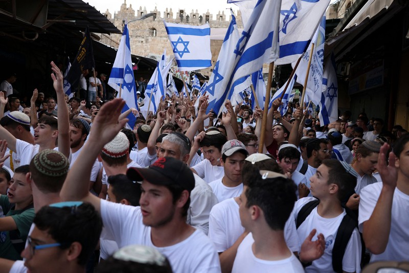 Yahudi Ultranasionalis Israel memegang bendera Israel saat mereka berbaris di kawasan Muslim kota tua Yerusalem pada 18 Mei 2023 di Yerusalem, Israel. Otoritas Israel akan mengizinkan orang-orang Yahudi Ortodoks berparade melalui Muslim Quarter Yerusalem dalam sebuah keputusan yang mengancam akan memicu kembali kekerasan di kota suci tersebut. (Amir Levy/Getty Images)