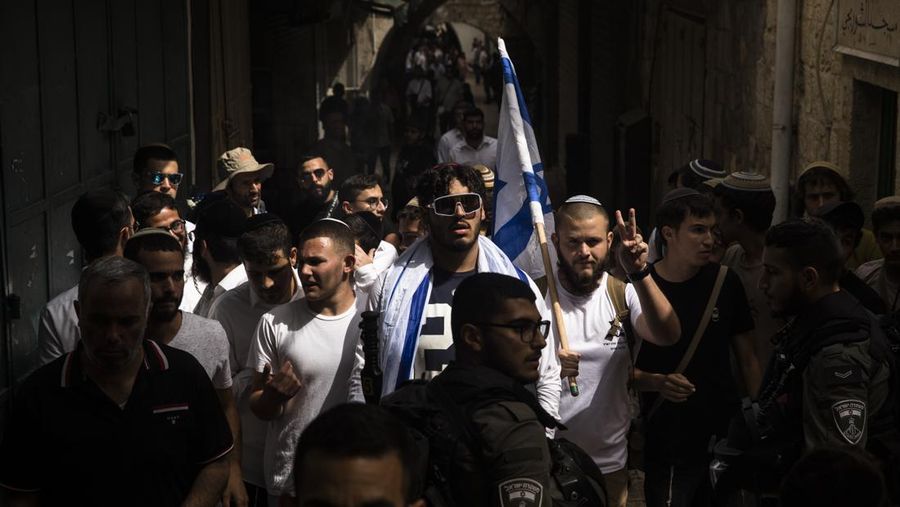 Yahudi Ultranasionalis Israel memegang bendera Israel saat mereka berbaris di kawasan Muslim kota tua Yerusalem pada 18 Mei 2023 di Yerusalem, Israel. Otoritas Israel akan mengizinkan orang-orang Yahudi Ortodoks berparade melalui Muslim Quarter Yerusalem dalam sebuah keputusan yang mengancam akan memicu kembali kekerasan di kota suci tersebut. (Amir Levy/Getty Images)