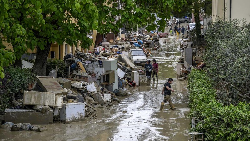 Warga membersihkan rumah mereka setelah hujan lebat menyebabkan banjir di wilayah Emilia Romagna utara Italia, pada 19 Mei 2023 di Faenza, Italia. Empat belas orang tewas dan ribuan orang telah dievakuasi dari rumah mereka setelah hujan deras menimbulkan kekacauan di wilayah Italia utara Emilia-Romagna, menyebabkan banjir dan tanah longsor yang parah. (Antonio Masiello/Getty Images)