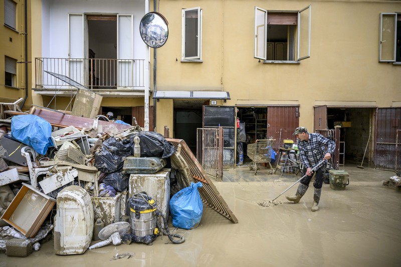Warga membersihkan rumah mereka setelah hujan lebat menyebabkan banjir di wilayah Emilia Romagna utara Italia, pada 19 Mei 2023 di Faenza, Italia. Empat belas orang tewas dan ribuan orang telah dievakuasi dari rumah mereka setelah hujan deras menimbulkan kekacauan di wilayah Italia utara Emilia-Romagna, menyebabkan banjir dan tanah longsor yang parah. (Antonio Masiello/Getty Images)