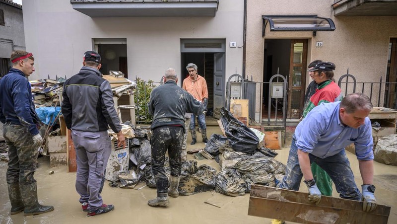 Warga membersihkan rumah mereka setelah hujan lebat menyebabkan banjir di wilayah Emilia Romagna utara Italia, pada 19 Mei 2023 di Faenza, Italia. Empat belas orang tewas dan ribuan orang telah dievakuasi dari rumah mereka setelah hujan deras menimbulkan kekacauan di wilayah Italia utara Emilia-Romagna, menyebabkan banjir dan tanah longsor yang parah. (Antonio Masiello/Getty Images)