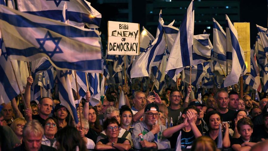 Demonstran mengangkat bendera dan plakat saat memprotes RUU pemeriksaan yudisial pemerintah Israel di Tel Aviv pada 20 Mei 2023. (AHMAD GHARABLI/AFP via Getty Images)