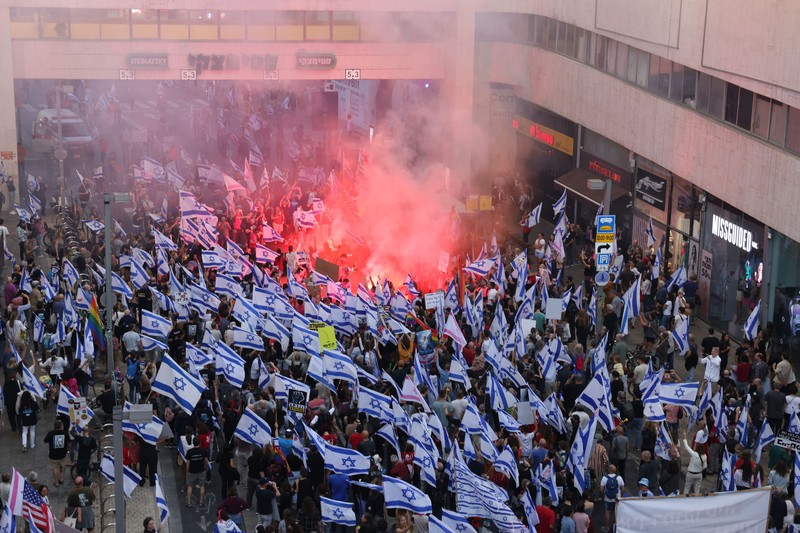 Demonstran mengibarkan bendera selama protes terhadap RUU perbaikan peradilan pemerintah Israel di Tel Aviv pada 20 Mei 2023. (AHMAD GHARABLI/AFP via Getty Images)