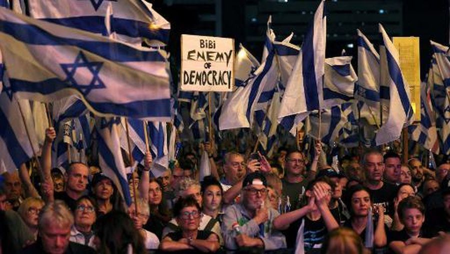 Demonstrators lift flags and placards during a protest against the Israeli government's judicial overhaul bill in Tel Aviv on May 20, 2023. (Photo by AHMAD GHARABLI / AFP)