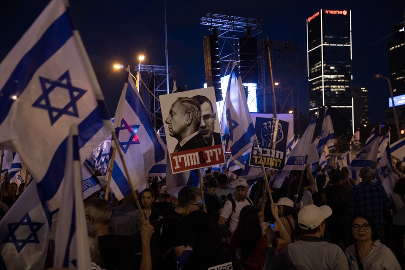 Demonstran mengibarkan bendera selama protes terhadap RUU perbaikan peradilan pemerintah Israel di Tel Aviv pada 20 Mei 2023. Demonstran mengibarkan bendera selama protes terhadap RUU perbaikan peradilan pemerintah Israel di Tel Aviv pada 20 Mei 2023. (AHMAD GHARABLI/AFP via Getty Images)