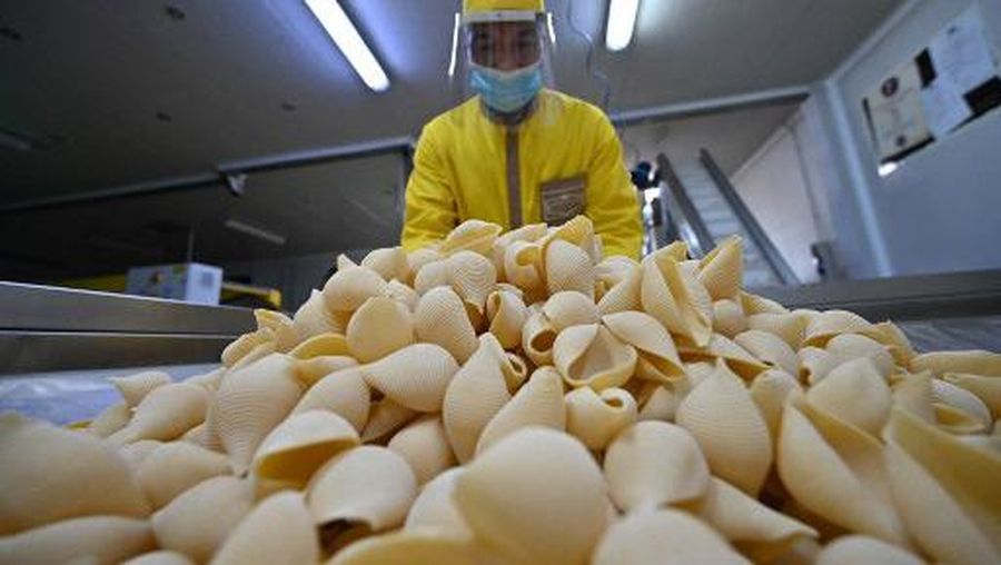 Co-owner with his three brothers and production manager of the Pasta di Gragnano factory near Naples, Antonino Moccia handles seashell pasta (conchiglie) during a working day on the production line on April 24, 2020 as the plant continues to produce with a reduced workforce during the country's lockdown aimed at curbing the spread of the COVID-19 infection, caused by the novel coronavirus. (Photo by ANDREAS SOLARO / AFP)