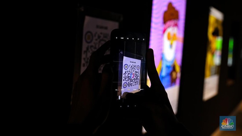 Pengunjung melihat karya Non-Fungible Token (NFT) yang dipamerkan di galeri fisik NFTOne, Jakarta, Rabu (24/5/2023). (CNBC Indonesia/Faisal Rahman)
