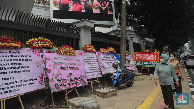 Warga melihat karangan bunga dari nasabah korban Koperasi Simpan Pinjam (KSP) Indosurya yang dipasang disepanjang jalur pedestrian kawasan kejagung, Jakarta, Rabu (24/5/2023). (CNBC Indonesia/Muhammad Sabki)